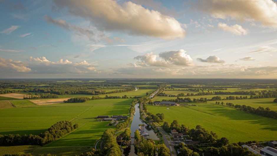 Aerial view of lush green fields and a river in Dieverbrug, DR, Nederland.