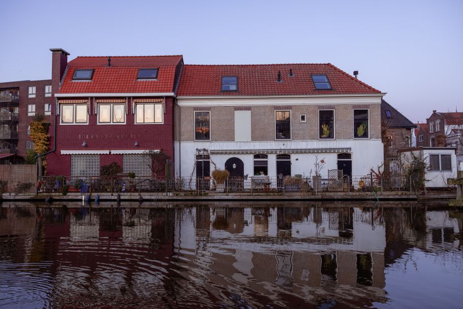 Picturesque canal houses in Gouda reflecting on the water at dusk.