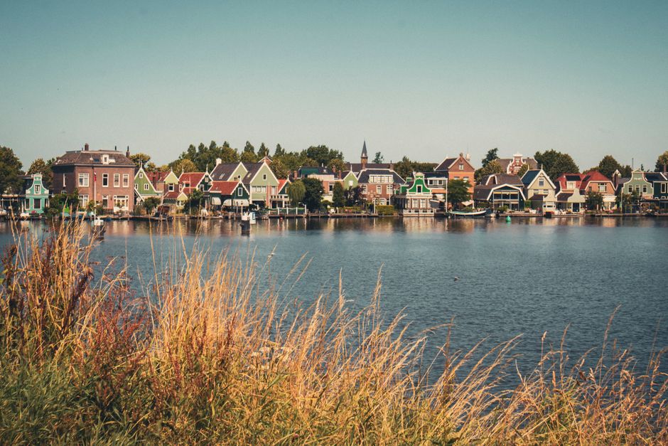 Picturesque view of Zaanse Schans in Zaandam with traditional houses and windmills by the water.